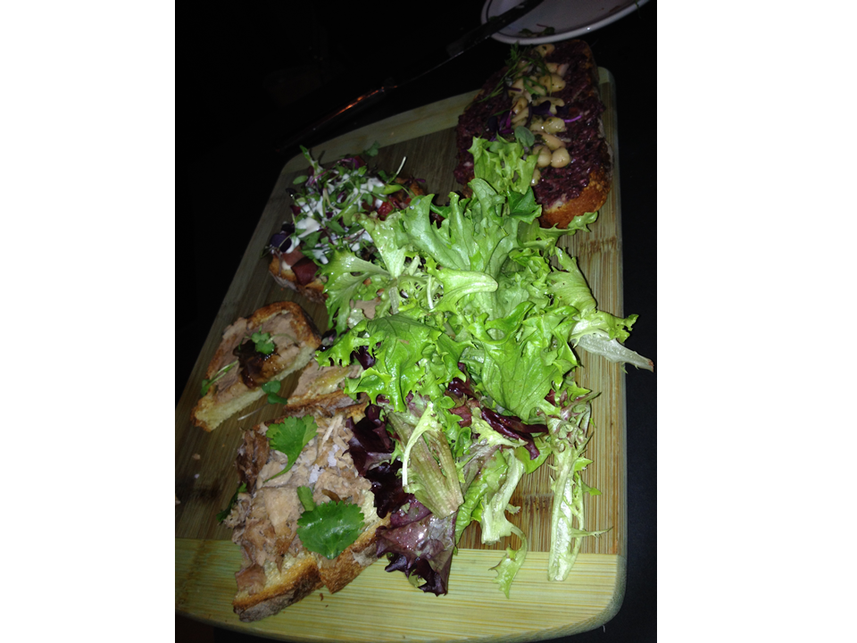 Figure 1. A bruschetta board after we dug into it. You can still see the remnants of the white bean, kalamata olive tapenade; lardon bacon, micro greens, tomato, house truffle aioli; and roast pork, lime, sea salt, and cilantro bruschettas. 